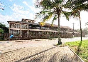 um edifício com uma palmeira em frente em Residências Garcez, paraíso à beira da praia Enseada, Guarujá no Guarujá