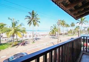 einen Balkon mit Blick auf den Strand und die Palmen in der Unterkunft Residências Garcez - Pantai Enseada - Vista Mar in Guarujá