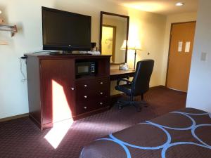 a hotel room with a television and a desk with a chair at Super 8 by Wyndham Lewiston in Lewiston