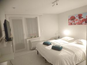 a white bedroom with a bed with two bags on it at Huize Fimo in Nieuwpoort