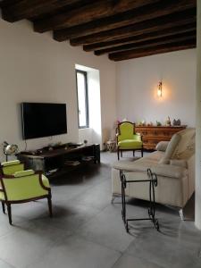 sala de estar con sofá, sillas y TV en L'Amalgam', en Ainay-le-Vieil