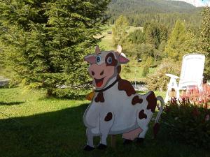 une statue d'une vache debout dans l'herbe dans l'établissement Residence La Pineta, à Padola