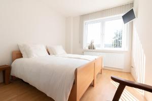 a white bedroom with a large bed and a window at Appartement Schin op Geul in Schin op Geul