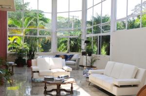 a living room with white furniture and large windows at Hotel Nosso Sonho in Itatiba