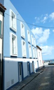 a blue building with white windows on a street at Royal Beach Hostel in Praia da Vitória