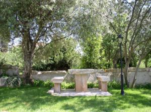 a stone bench sitting in the grass next to a wall at Apartments Paloma Blanca in Medulin