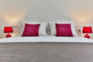 a white bed with red pillows and two red lamps at Apartments Sidro in Dobra Voda