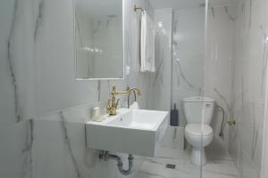 a white bathroom with a sink and a toilet at Neratzia Rooms in Athens