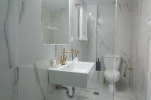 a white bathroom with a sink and a toilet at Neratzia Rooms in Athens +32 photos