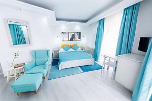 um quarto com uma cama, uma cadeira e uma mesa em Relax Comfort Suites Hotel em Bucareste