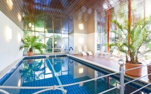a swimming pool with plants in a building at Wittelsbacher Hof Swiss Quality Hotel in Garmisch-Partenkirchen