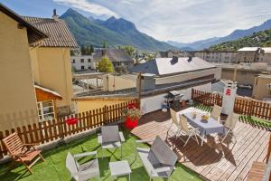 um pátio exterior com uma mesa, cadeiras e montanhas em Apartment Briancon em Briançon