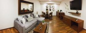 a living room with a couch and a television at Hotel Plaza Catedral in Gómez Palacio