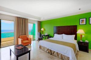 Cette chambre comprend un lit et un mur vert. dans l'établissement Holiday Inn Campeche, an IHG Hotel, à Campeche