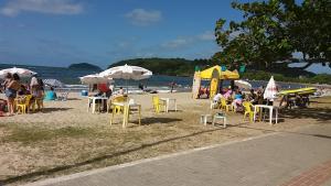 a group of people sitting on a beach with chairs and umbrellas at Casa temporada Beto Carrero in Penha