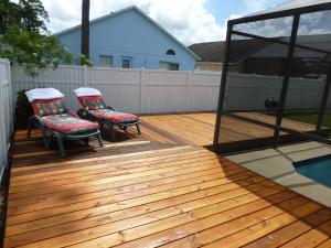 una terraza de madera con 2 sillas y una piscina en The Florida Pad en Kissimmee
