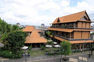 a large building with brown roofs and trees and a street at Omah Sinten Heritage Hotel & Resto in Solo
