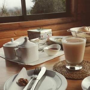 una mesa cubierta con platos y cuencos y un vaso de leche en Terrazas del Palena en La Junta