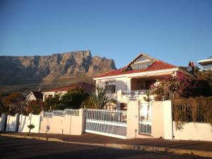 a house with a fence with a mountain in the background at Garden apartment Bay View in Cape Town