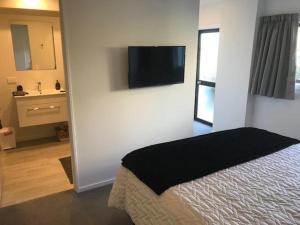 1 dormitorio con 1 cama y TV en la pared en Abel Tasman Kaiteriteri B & B, en Kaiteriteri