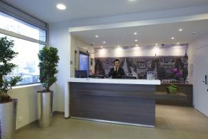 a man sitting at a reception desk in a lobby at Citadines Montparnasse Paris in Paris