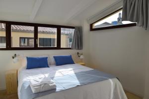 sypialnia z łóżkiem z niebieskimi poduszkami i oknem w obiekcie Ca Sa Tieta w mieście Alaró