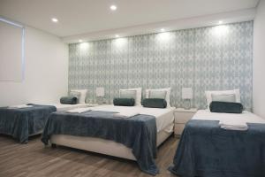 a room with two beds and a wall with patterns at 4U Lisbon VI Guesthouse Airport in Lisbon