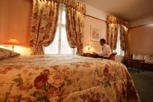 a man sitting at a bed in a hotel room at Hotel Victoria in Pärnu