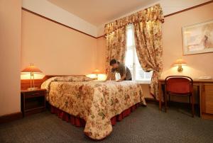 a man sitting on a bed in a hotel room at Hotel Victoria in Pärnu
