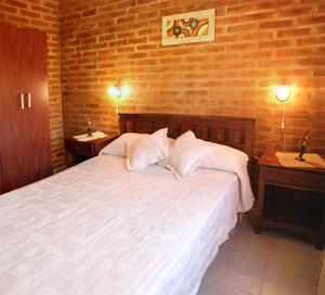 a bedroom with a large white bed with two tables at CABAÑAS AGUARI in Santa Rosa de Calamuchita