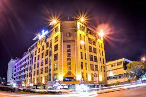 un gran edificio amarillo con una torre de reloj por la noche en Shervinton Executive Boutique Hotel, en Tawau