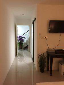 a hallway with a table and a television on a wall at Baba Guest House in Kamala Beach