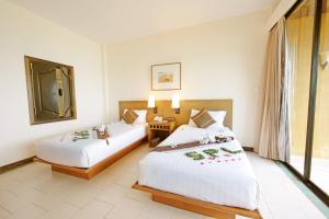 a hotel room with two beds and a mirror at Supalai Scenic Bay Resort And Spa, SHA Extra Plus in Por Bay