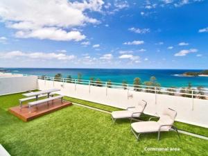a balcony with a table and chairs and the ocean at Namely Manly in Sydney