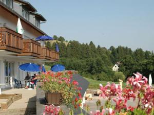 eine Terrasse mit Blumen und blauen Sonnenschirmen sowie ein Gebäude in der Unterkunft Wohnpark Schwarzwaldblick Bernau in Bernau im Schwarzwald