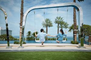 a couple jumping on a swing at a resort at Grande Centre Point Pattaya in Pattaya