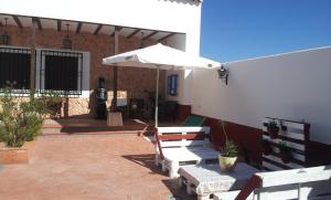 a patio with a white umbrella and chairs and a table at Casa Rural con jacuzzi y pista de padel - Casa de Pacas in Bolaños de Calatrava