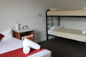 a room with two bunk beds and a bed with towels at Hotel Beach House Nambour in Nambour