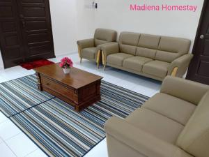 a living room with a couch and a coffee table at Madiena Homestay in Kampung Gurun +2 photos