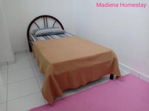 a bedroom with a bed in a room with a rug at Madiena Homestay in Kampung Gurun