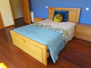 a wooden bed with a blue and yellow pillow on it at Merck Villa Gerês in Rio Caldo +39 photos