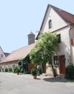 a white building with a tree next to a street at Kreuzerhof Hotel Garni in Rothenburg ob der Tauber