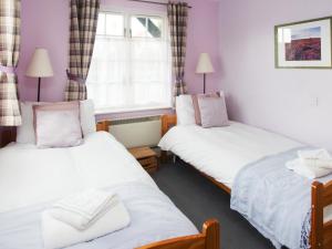 two twin beds in a room with a window at 1 Bell Lodge, Thorpeness in Thorpeness