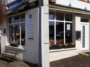 a bench outside of a store with flowers in windows at Hotel De La Gare in Sainte-Gauburge-Sainte-Colombe