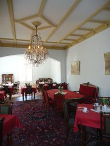 ein Esszimmer mit roten Tischen, Stühlen und einem Kronleuchter in der Unterkunft PP Pension Potsdam in Potsdam