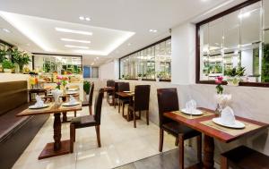 um restaurante com mesas e cadeiras de madeira e janelas em S Central Hotel and Spa em Hanói