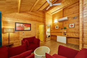 a living room with wooden walls and red chairs at Bodhiwoods Resorts in Mahabalipuram