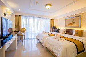 um quarto de hotel com duas camas e uma televisão de ecrã plano em Art De Sea Hua Hin em Hua Hin