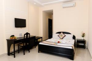 a bedroom with a bed and a desk and a television at Hon Rom Central Beach Resort in Mui Ne