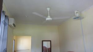 
a room with a ceiling fan and a white wall at Benarat Lodge in Mulu

